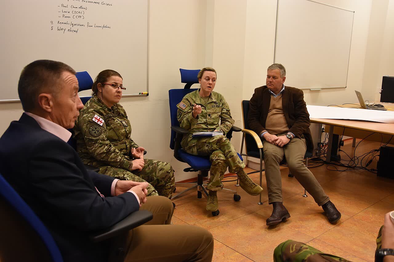 Uczestnicy ćwiczenia prowadzą naradę w niewielkim gronie, siedząc przy tablicy z planem spotkania.